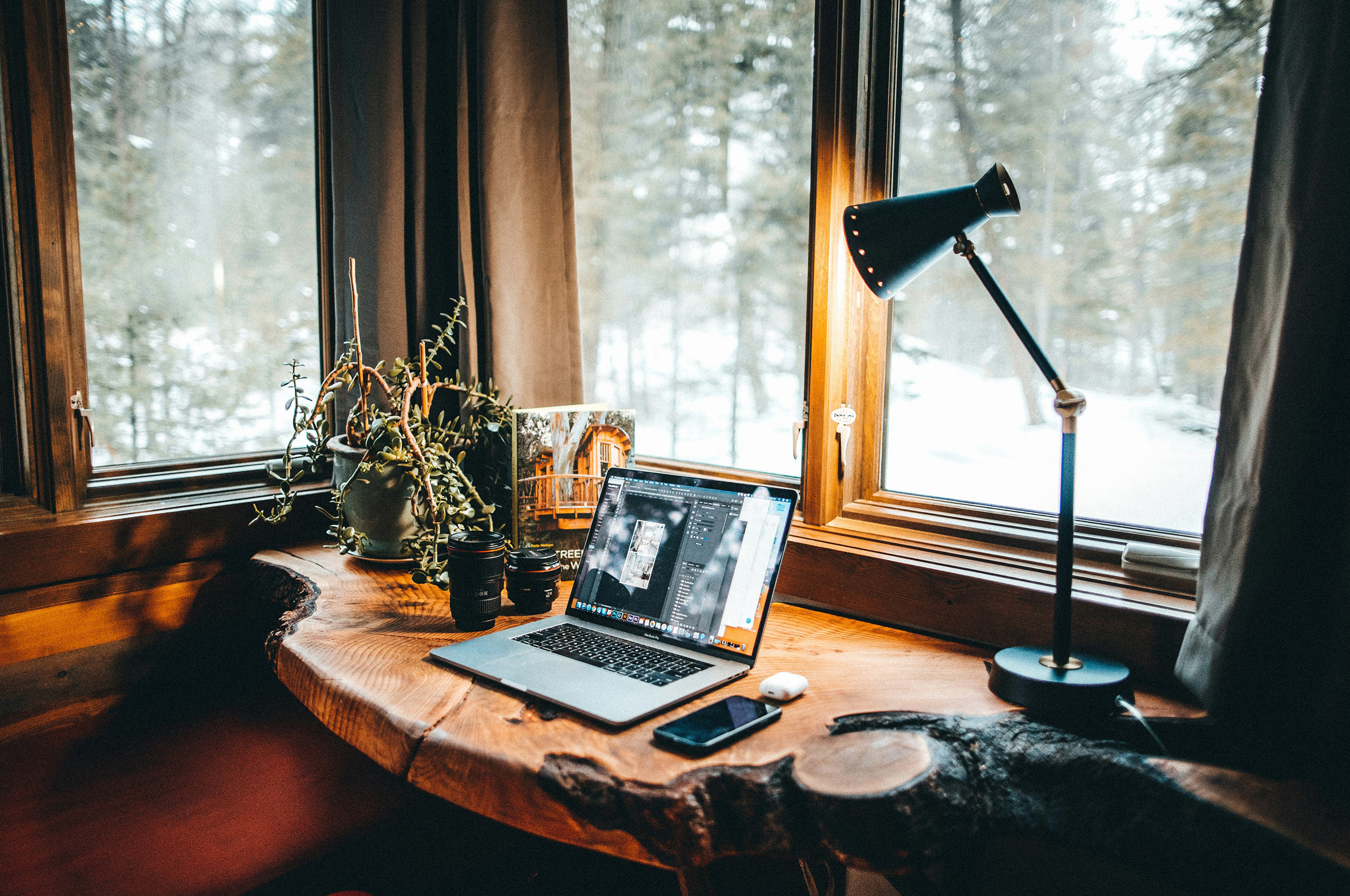 An image of a laptop on a desk by some large windows