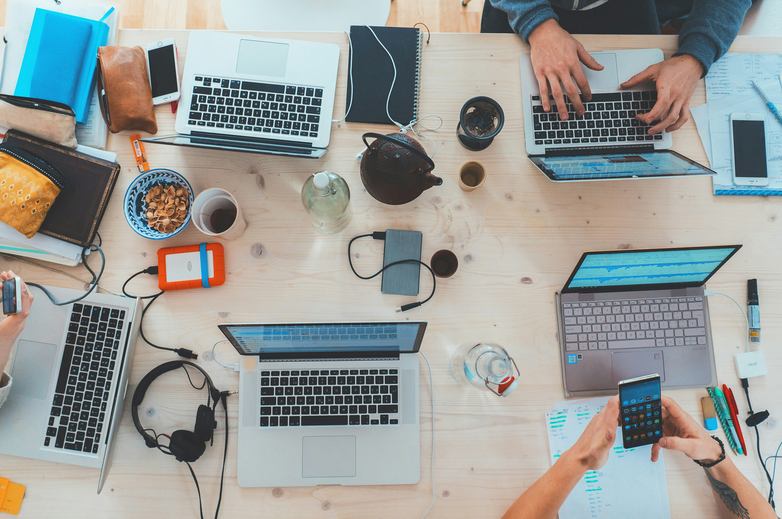 A birds eye view of a table with several people working on their laptops