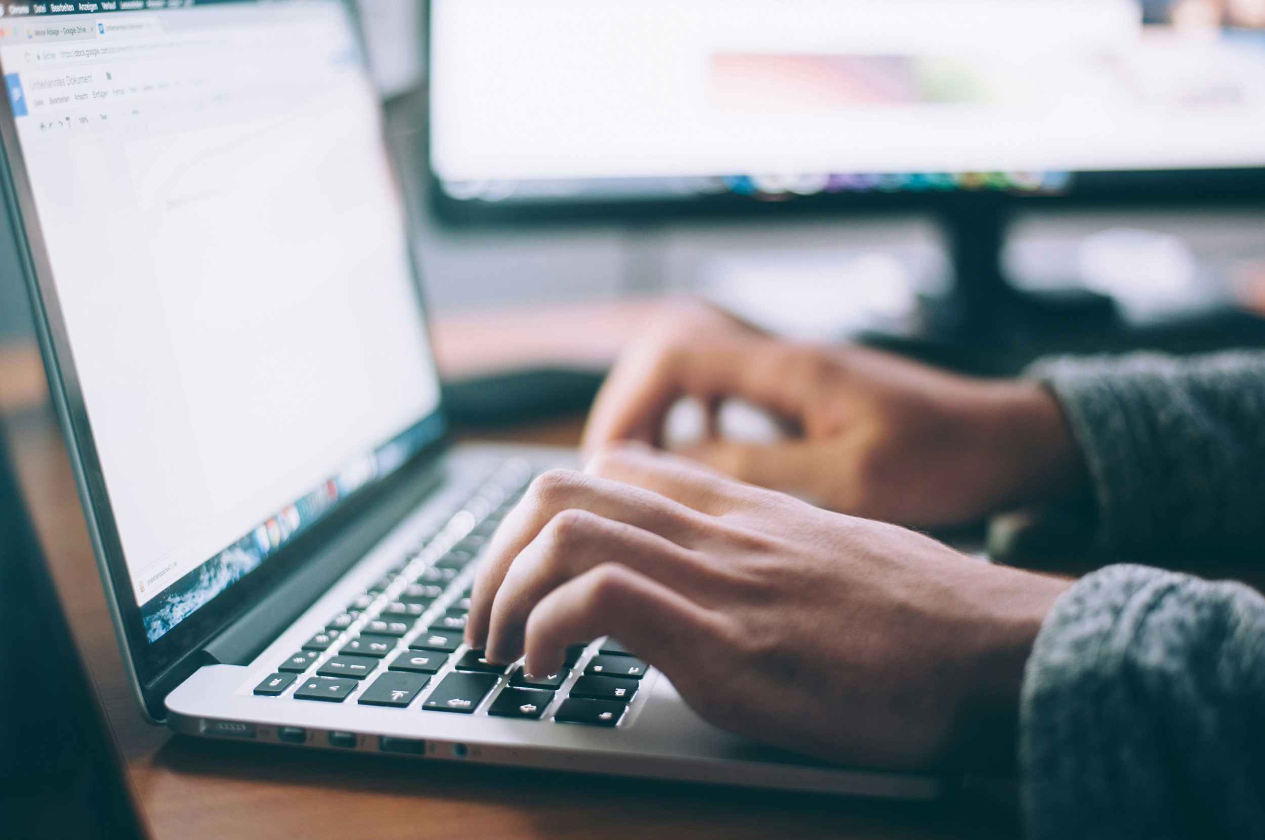 An image of hands typing at a laptop keyboard